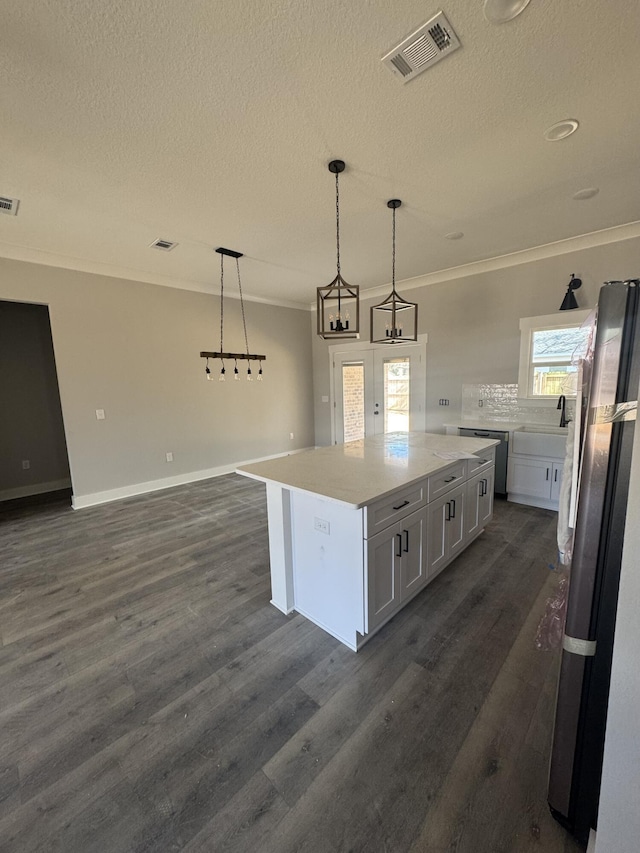 kitchen featuring crown molding, visible vents, dark wood-type flooring, and freestanding refrigerator