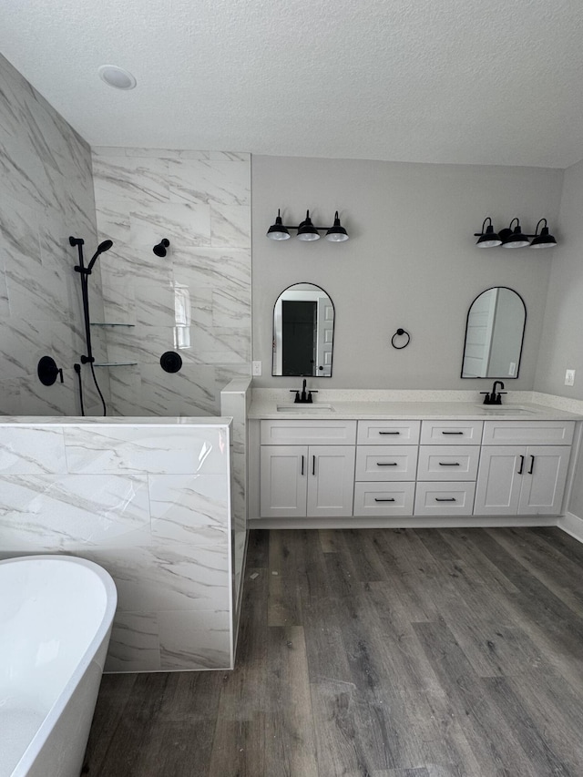 full bathroom featuring a walk in shower, double vanity, a sink, and wood finished floors