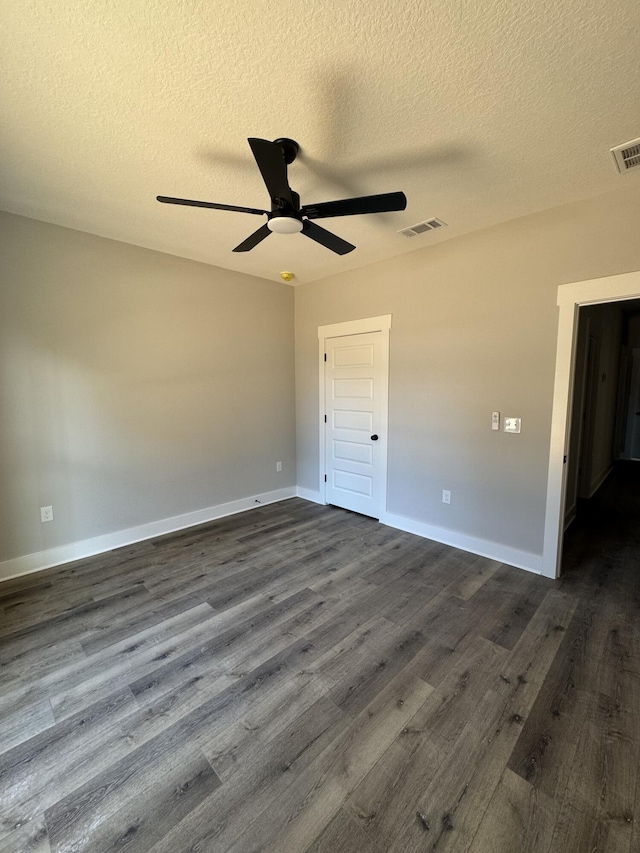 spare room featuring a ceiling fan, baseboards, visible vents, and dark wood-type flooring