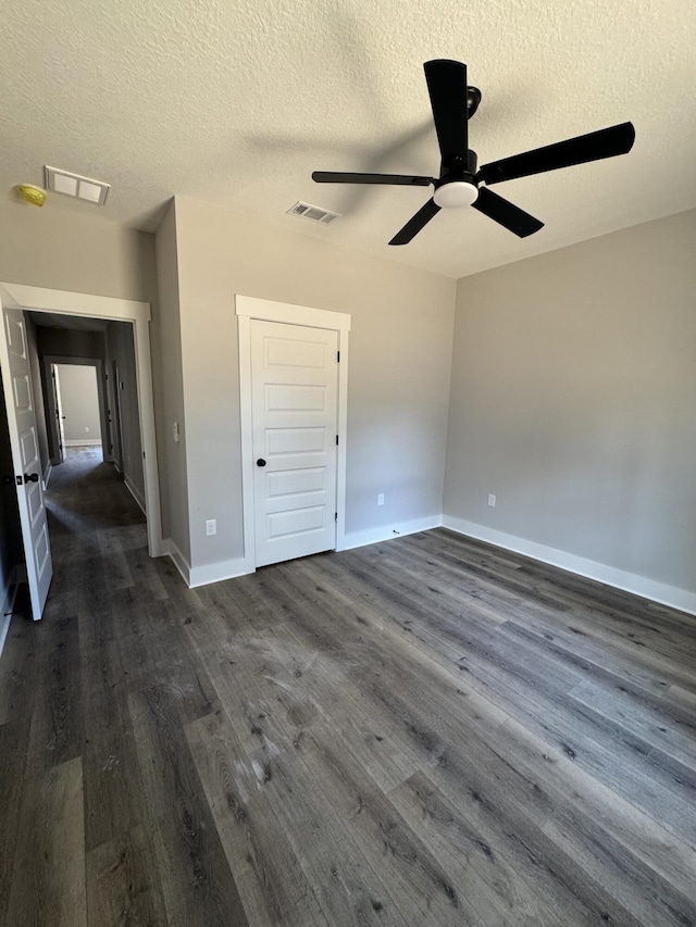 unfurnished bedroom featuring a ceiling fan, baseboards, visible vents, and dark wood-type flooring