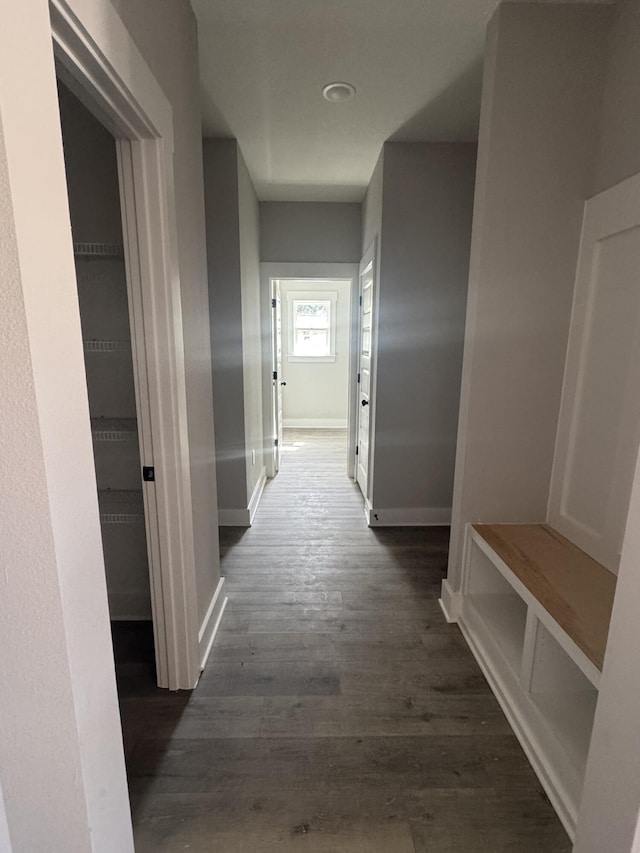 corridor featuring dark wood-style flooring and baseboards