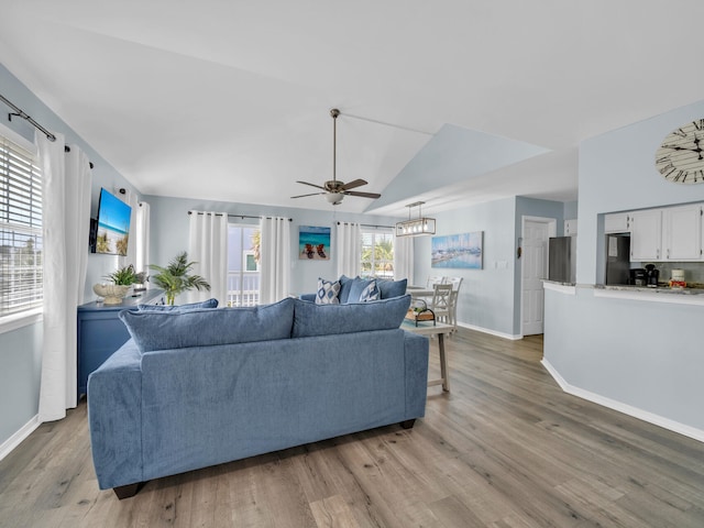 living area with lofted ceiling, baseboards, a ceiling fan, and light wood-style floors