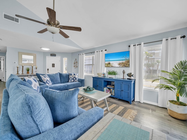 living room featuring light wood-type flooring, visible vents, vaulted ceiling, and a wealth of natural light