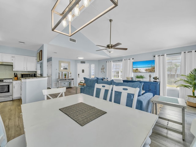 dining room with a wealth of natural light, visible vents, lofted ceiling, and light wood finished floors