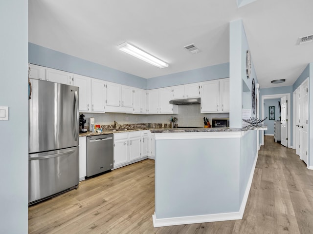 kitchen featuring white cabinetry, under cabinet range hood, visible vents, and appliances with stainless steel finishes