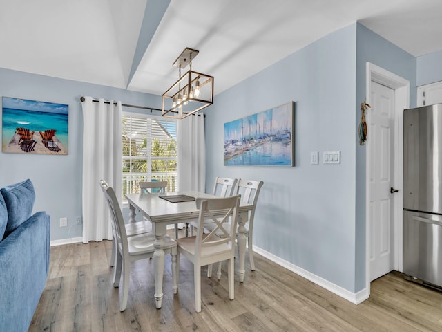 dining area with light wood-style flooring, baseboards, and an inviting chandelier