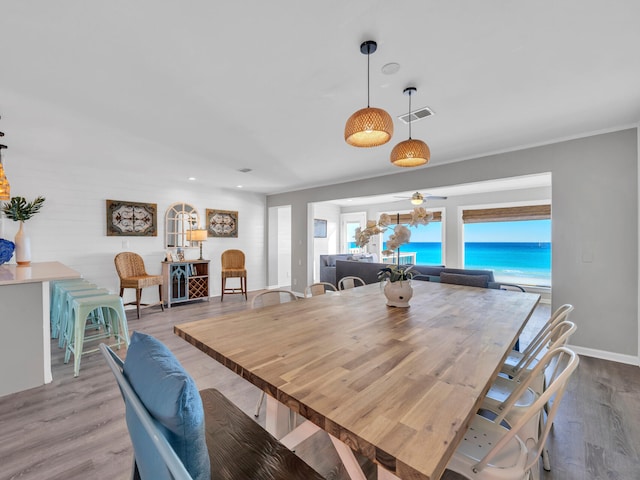 dining room with a water view, baseboards, visible vents, and wood finished floors