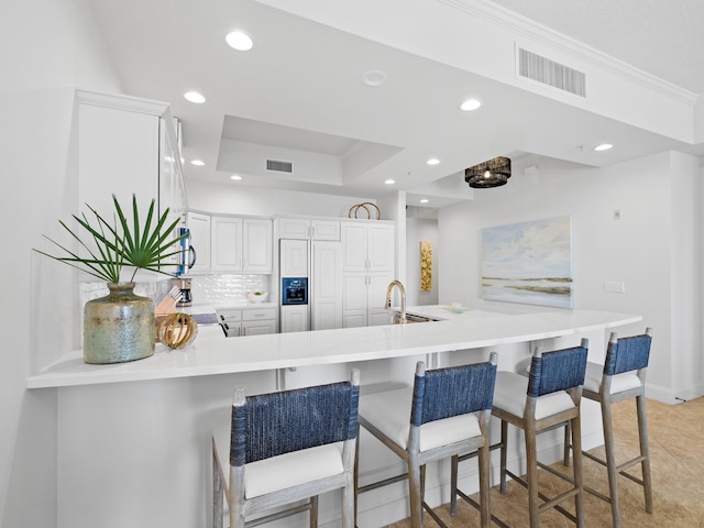 kitchen featuring visible vents, a peninsula, a tray ceiling, light countertops, and recessed lighting