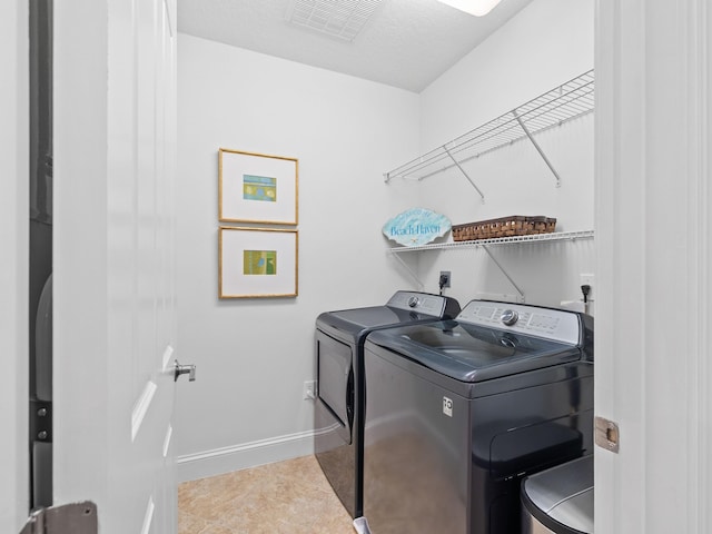 laundry room featuring laundry area, baseboards, visible vents, washer and clothes dryer, and tile patterned floors