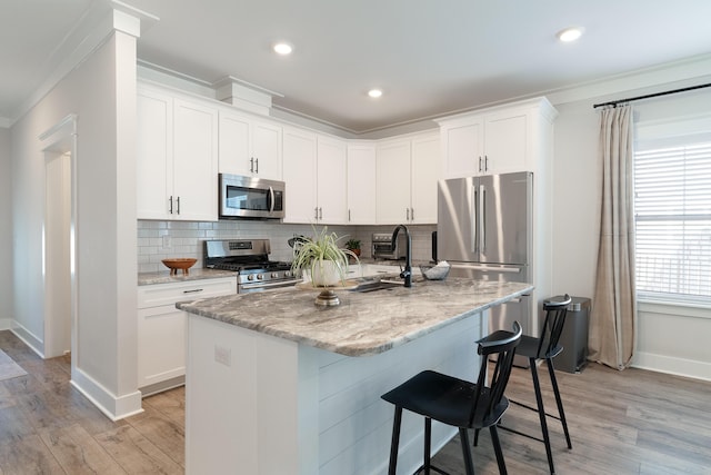 kitchen featuring appliances with stainless steel finishes, a kitchen island with sink, and white cabinetry