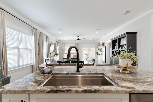 kitchen featuring stone countertops, a sink, visible vents, open floor plan, and ornamental molding