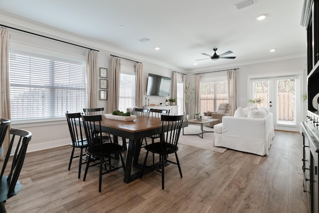 dining area featuring light wood-type flooring, visible vents, crown molding, and baseboards