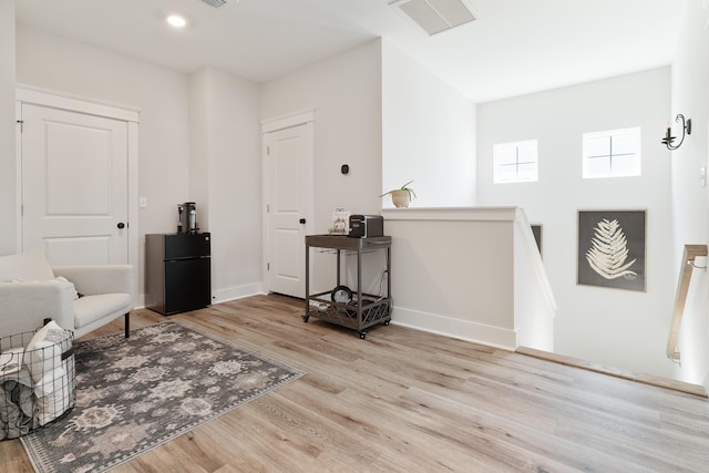 sitting room with visible vents, light wood-style flooring, an upstairs landing, and baseboards