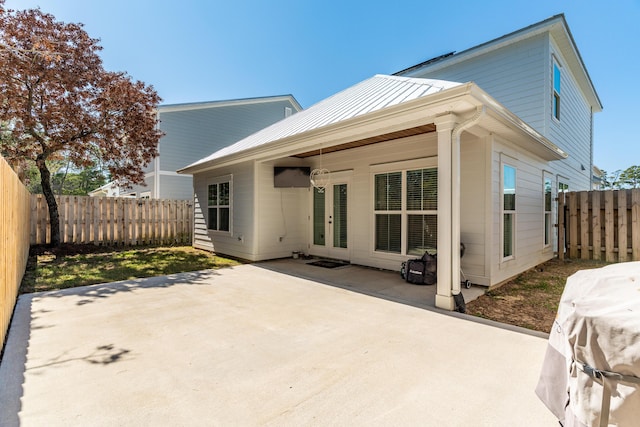 back of property featuring a standing seam roof, a patio area, metal roof, and a fenced backyard