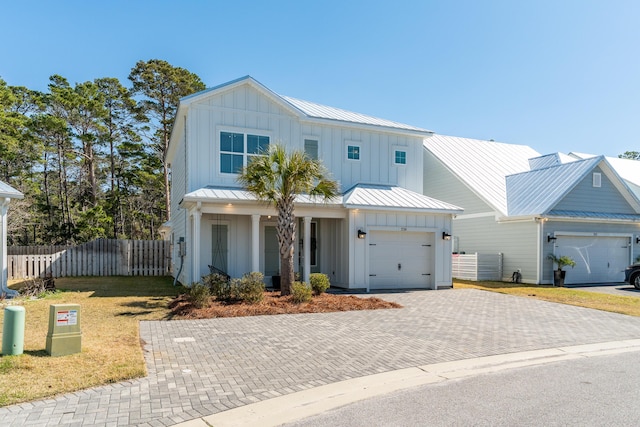 view of front of house featuring decorative driveway, board and batten siding, a standing seam roof, fence, and metal roof