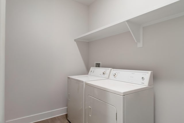 laundry area featuring laundry area, wood finished floors, washing machine and clothes dryer, and baseboards