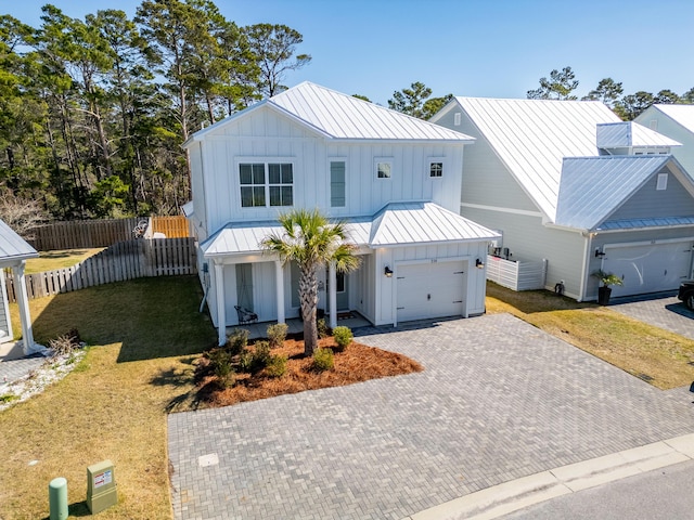 modern farmhouse with a standing seam roof, metal roof, board and batten siding, and fence