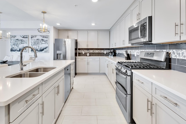 kitchen with white cabinets, appliances with stainless steel finishes, light countertops, pendant lighting, and a sink