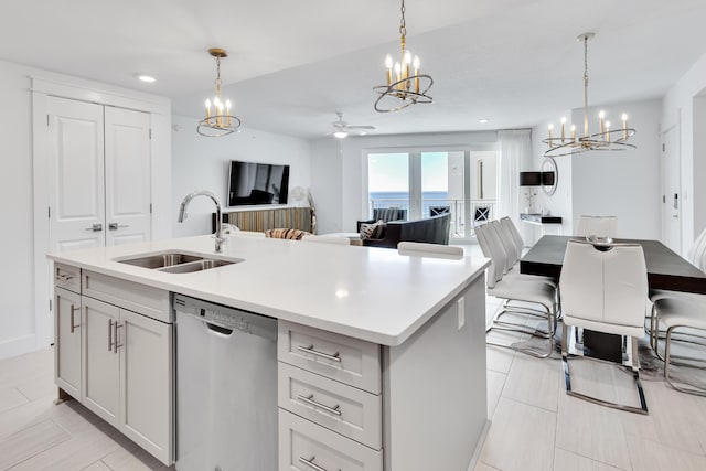 kitchen featuring a sink, open floor plan, light countertops, stainless steel dishwasher, and an island with sink