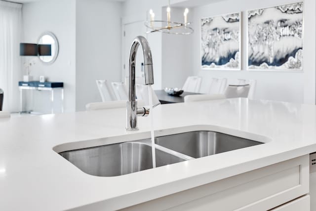 kitchen featuring a chandelier, light countertops, a sink, and hanging light fixtures