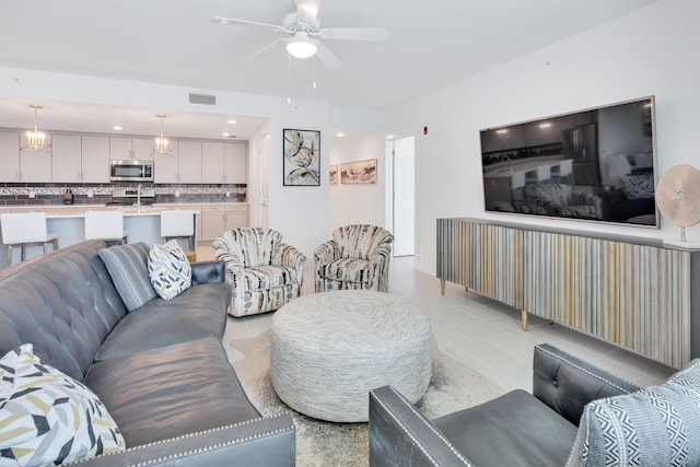 living area with ceiling fan with notable chandelier