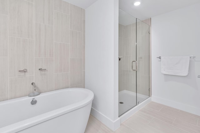 full bathroom with a freestanding bath, a stall shower, and baseboards