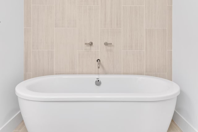 full bath featuring a soaking tub, tile walls, and baseboards