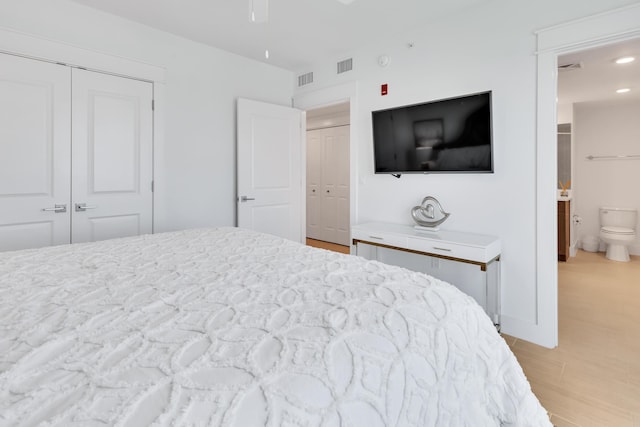 bedroom featuring light wood-type flooring, connected bathroom, and visible vents