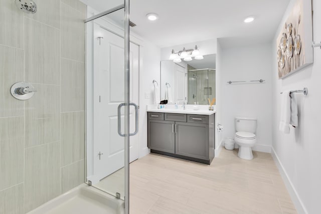 full bathroom with a stall shower, baseboards, vanity, and toilet