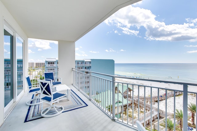 balcony with a water view and a view of the beach