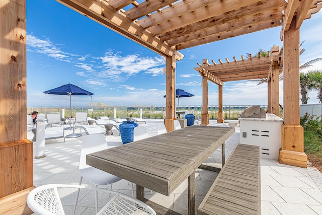 view of patio with outdoor dining area, an outdoor kitchen, a water view, and a pergola