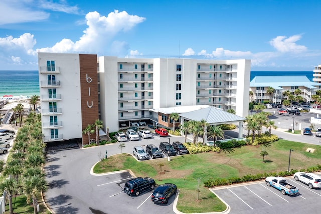 view of building exterior with uncovered parking and a water view