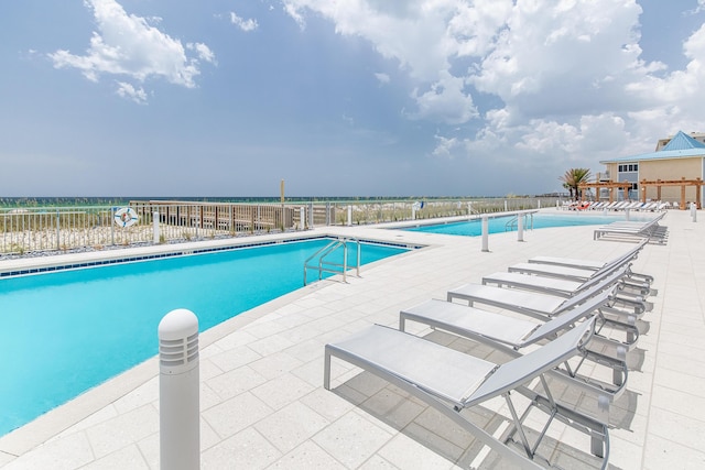 pool featuring a patio area, fence, and a water view