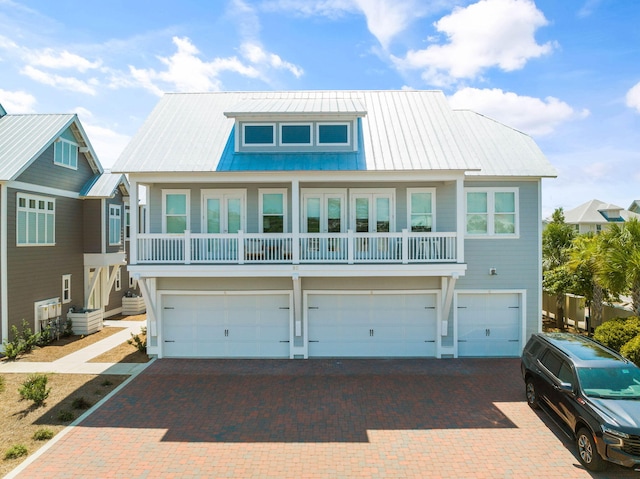 coastal home with a garage, central air condition unit, metal roof, and decorative driveway