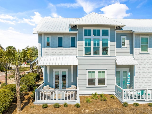 back of property with metal roof, french doors, and a standing seam roof