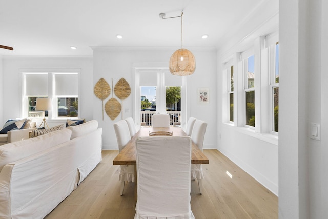 dining space with ornamental molding, baseboards, and light wood finished floors