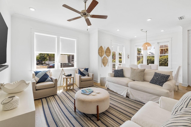 living area featuring ornamental molding, a healthy amount of sunlight, visible vents, and wood finished floors