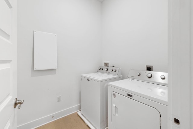 washroom featuring washing machine and dryer, laundry area, baseboards, and light wood finished floors