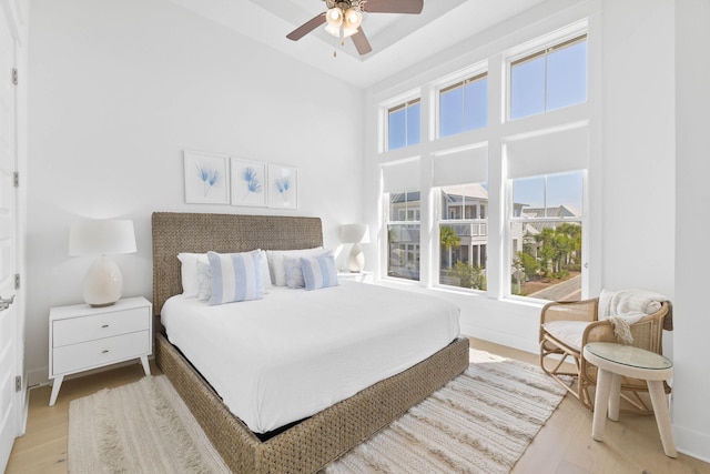 bedroom with light wood-style flooring, baseboards, and ceiling fan