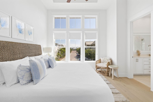 bedroom featuring ceiling fan, light wood finished floors, and ensuite bathroom