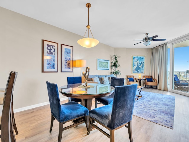 dining room featuring light wood-style flooring, baseboards, and ceiling fan