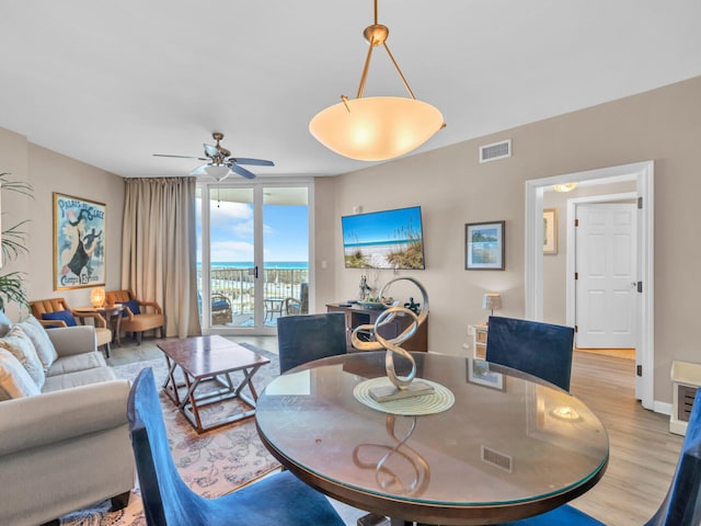 dining room with visible vents, baseboards, expansive windows, light wood-style floors, and a ceiling fan