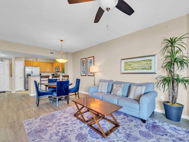 living area with visible vents, ceiling fan, baseboards, and light wood-style floors