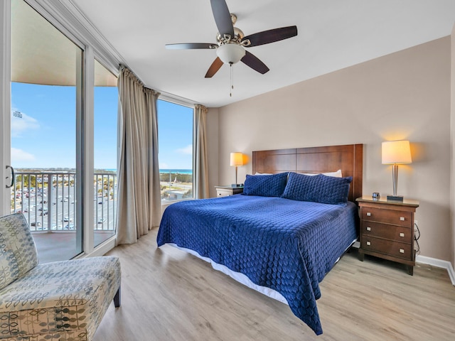 bedroom featuring light wood-style flooring, baseboards, access to exterior, and floor to ceiling windows