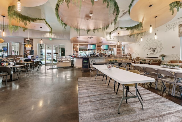 dining area with a towering ceiling, french doors, and concrete flooring