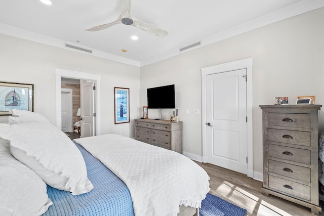 bedroom with ornamental molding, wood finished floors, visible vents, and baseboards