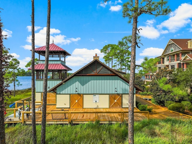 back of house featuring board and batten siding, a standing seam roof, a deck with water view, and metal roof