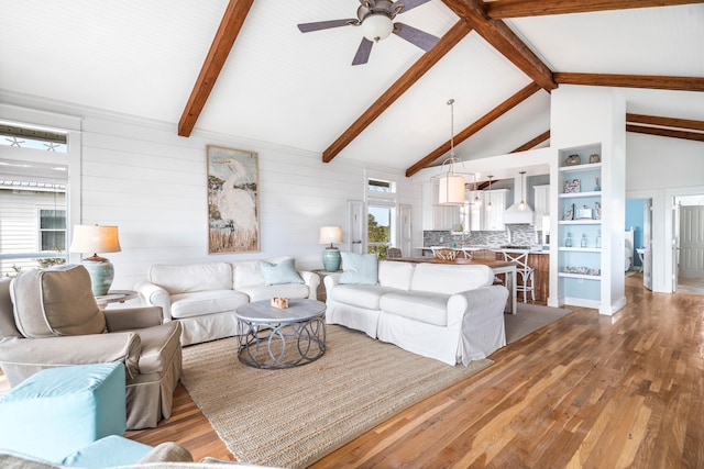 living room with ceiling fan, high vaulted ceiling, wood finished floors, and beam ceiling