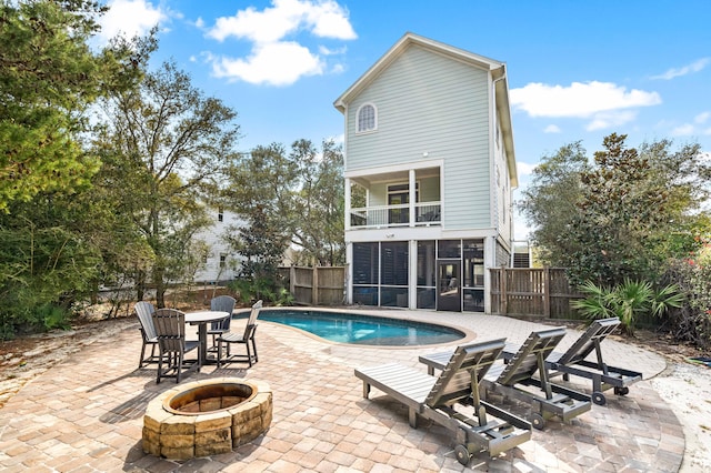 view of swimming pool featuring a fenced in pool, a sunroom, a fenced backyard, and a fire pit