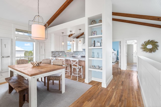 dining room featuring high vaulted ceiling, beamed ceiling, and wood finished floors